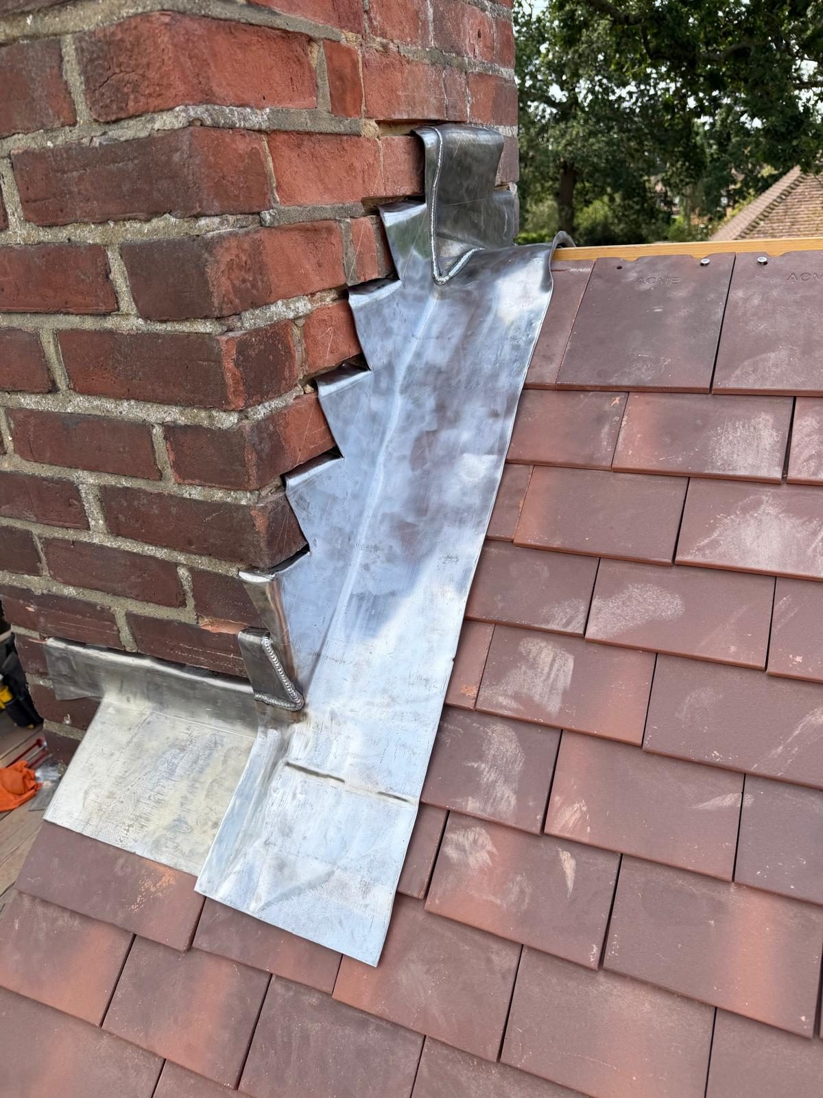 Stepped lead flashing dressed around a brick chimney on a new tiled roof